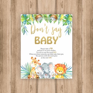 May include: A white card with gold text that says "Don't say BABY".  The card has a jungle theme with green leaves, a giraffe, an elephant, and a lion.  The text below the title says "Please take a PIN and put it on your clothes. Try not to say the word BABY. When you hear someone say baby take their pin. The person with the most pins at the end WINS!"