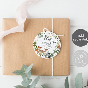 May include: Round thank you tag with a woodland theme. The tag features a wreath of green leaves with a fox, deer, and raccoon inside. The text reads "Thank you! Melissa's Baby Shower June 20, 2020".