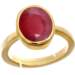 May include: A gold ring with a large, oval-shaped, red ruby gemstone.