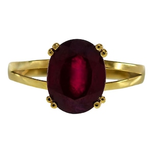 May include: A gold ring with a large, oval-shaped ruby gemstone. The ruby is a deep red color and is set in a simple, elegant setting.