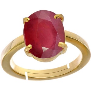 May include: A gold ring with a large, oval-shaped, red ruby gemstone. The ring has a simple band and the ruby is set in a prong setting.