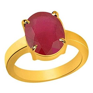 May include: A gold ring with a large, oval-shaped ruby gemstone. The ruby is a deep red color and has a faceted cut.