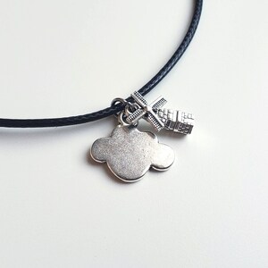 May include: A black cord necklace with a silver charm of a cloud and a windmill.