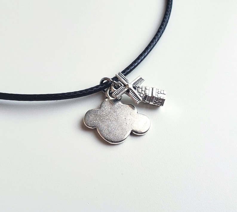 May include: A black cord necklace with a silver charm of a cloud and a windmill.
