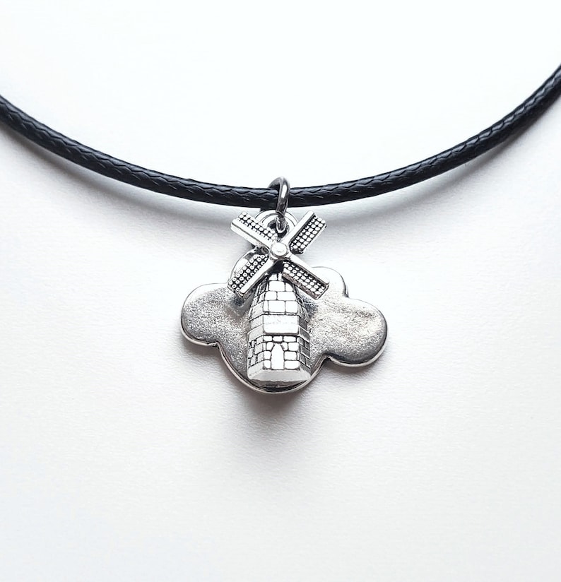 May include: A silver necklace with a black cord and a charm of a windmill on a cloud.