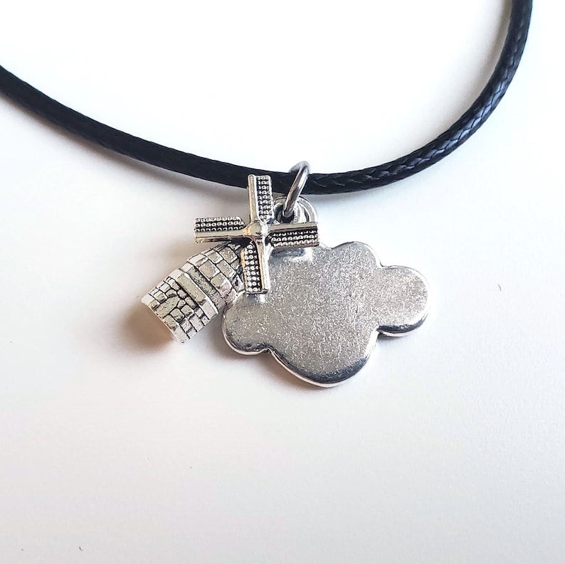 May include: A silver necklace with a charm of a windmill and a cloud. The necklace is on a black cord.