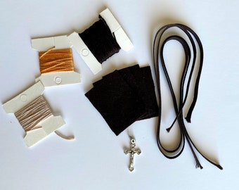 May include: A kit for making a beaded cross necklace. It includes three spools of thread, two pieces of brown fabric, a silver cross charm, and a length of brown cord.