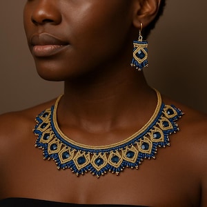 Puede incluir: Un collar y pendientes a juego de macramé azul y dorado. El collar presenta un patrón geométrico repetitivo con detalles en azul y cordón dorado. Los pendientes tienen un diseño similar, con un gancho dorado.