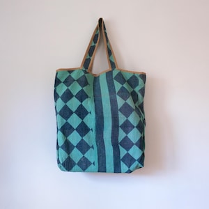 May include: A green and black checkered tote bag with brown leather handles.