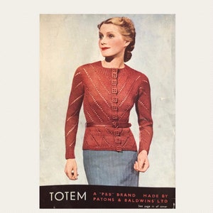 Puede incluir: Un cárdigan de punto rojo con cierre de botones y un patrón de rombos. El cárdigan lo lleva una mujer con un cinturón alrededor de la cintura. El texto "TOTEM A "P&B" BRAND MADE BY PATONS & BALDWINS LTD See page iii of cover" está impreso en la parte inferior de la imagen.