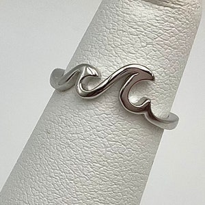 May include: A silver wave ring. The ring is made of metal and features a wave design.