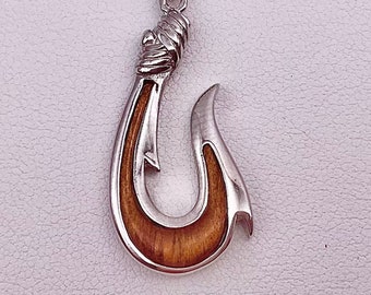 May include: A silver chain necklace with a silver and brown wood hook pendant. The hook is a traditional Hawaiian fishing hook.