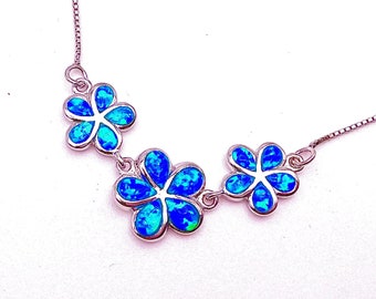 May include: A silver chain necklace with three blue opal flower pendants.