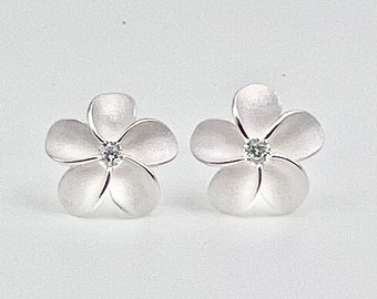 Può includere: Un paio di orecchini a bottone in argento a forma di fiore con un brillante trasparente al centro di ogni fiore.
