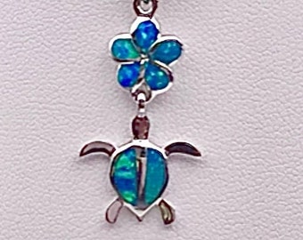 May include: A silver necklace with a blue opal flower charm and a blue opal turtle charm.