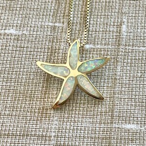 May include: A gold chain necklace with a white opal starfish pendant.