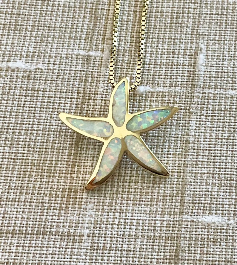 May include: A gold chain necklace with a white opal starfish pendant.