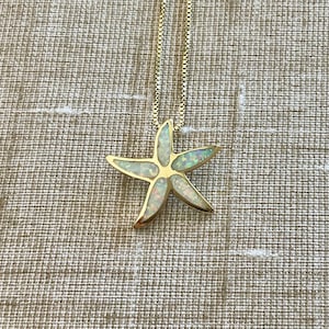 May include: A gold chain necklace with a white opal starfish pendant.