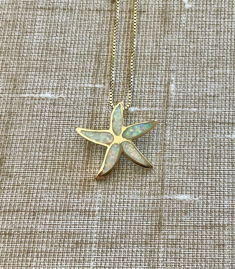 May include: A gold chain necklace with a white opal starfish pendant.