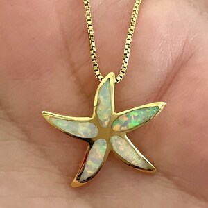May include: A gold chain necklace with a white opal starfish pendant.