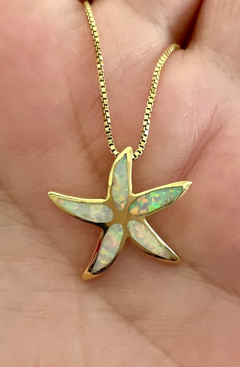 May include: A gold chain necklace with a white opal starfish pendant.