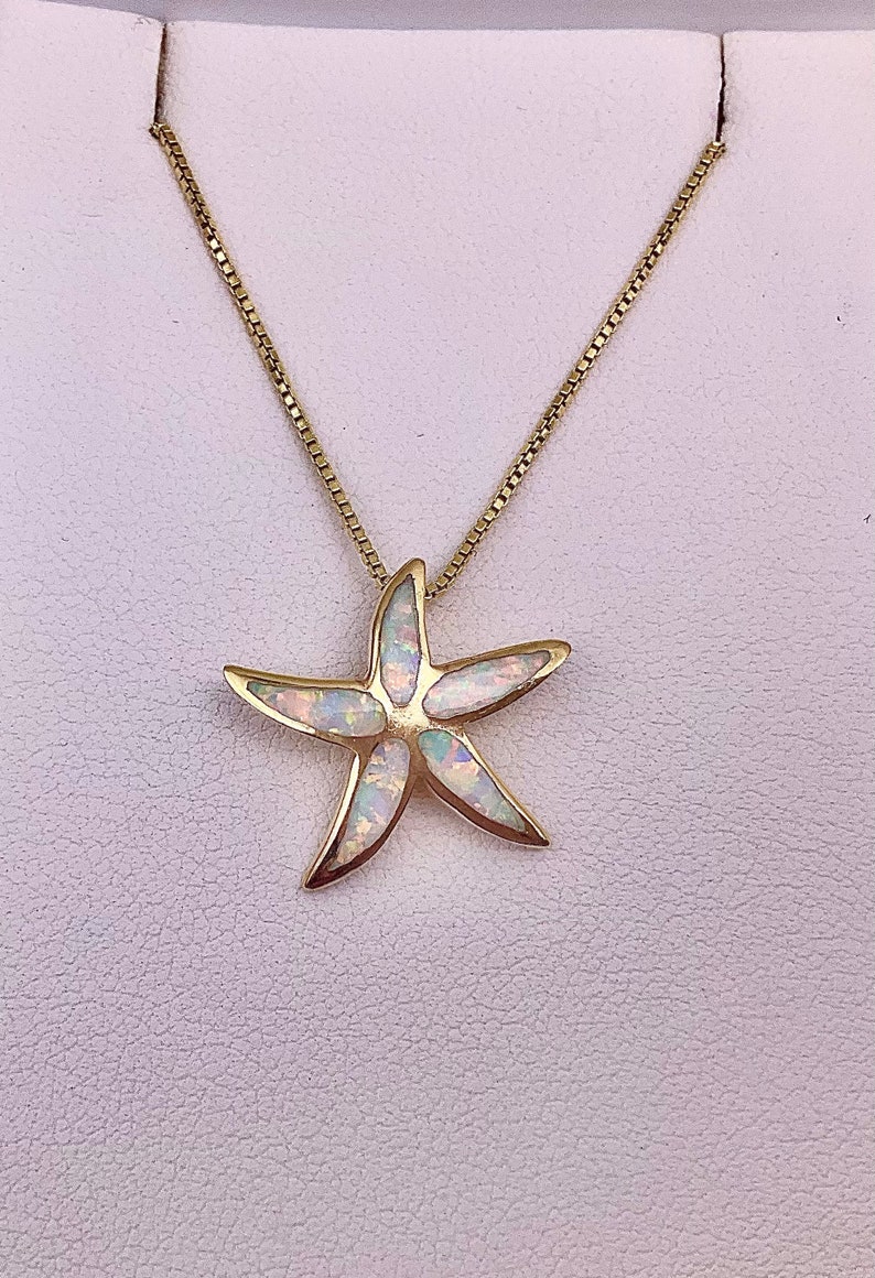 May include: A gold chain necklace with a white opal starfish pendant.
