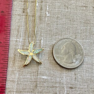 May include: A gold chain necklace with a white opal starfish pendant. The pendant is about the size of a US quarter.