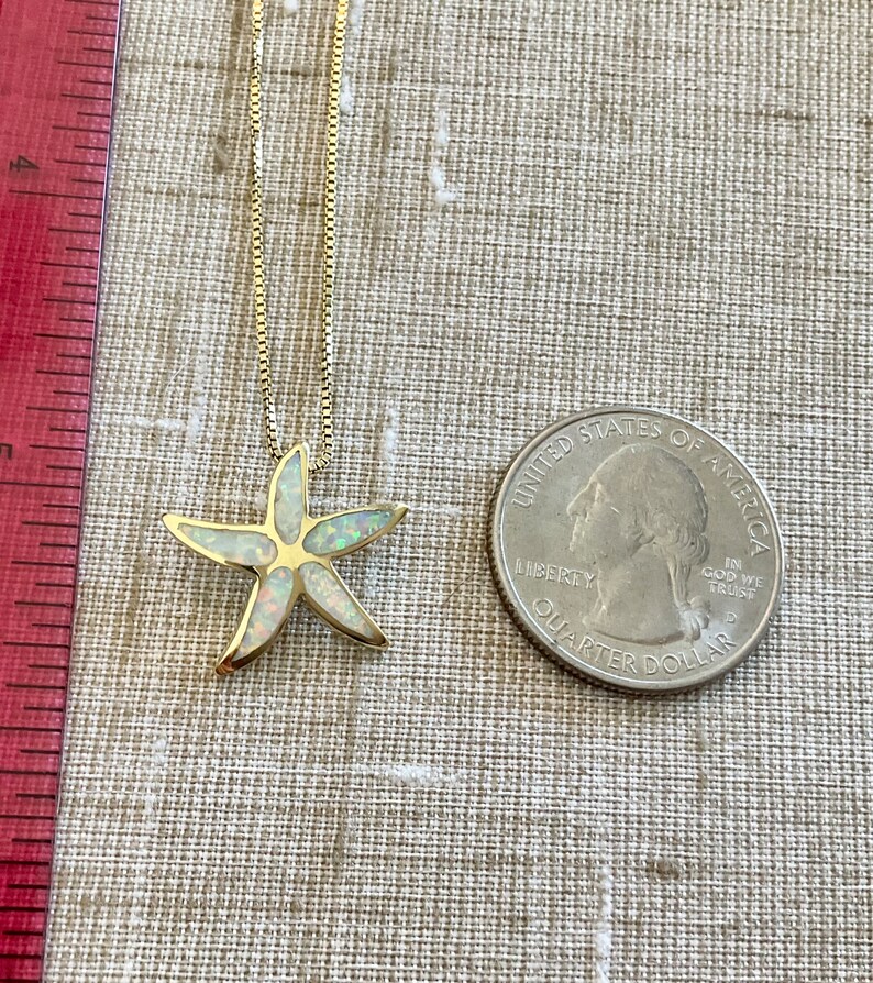 May include: A gold chain necklace with a white opal starfish pendant. The pendant is about the size of a US quarter.