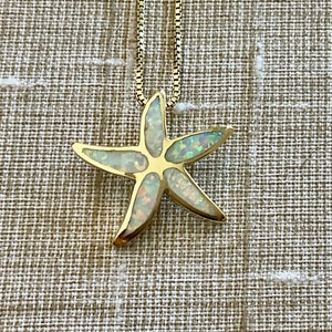 May include: A gold chain necklace with a white opal starfish pendant.