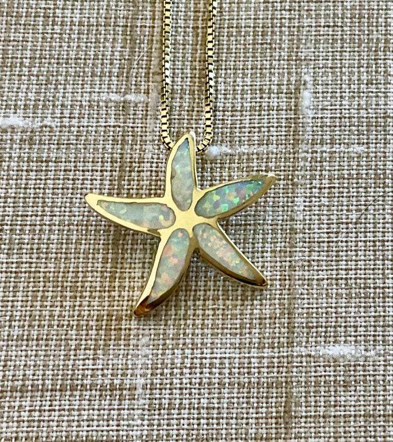 May include: A gold chain necklace with a white opal starfish pendant.