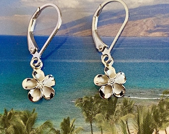 May include: Silver dangle earrings with a small white flower charm. The flower has a small clear stone in the centre.