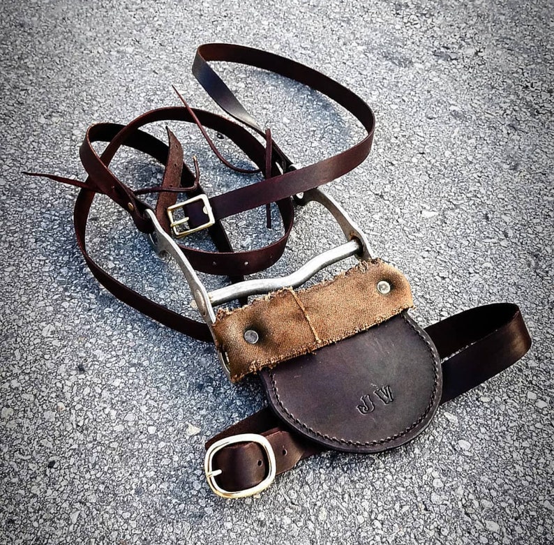 May include: A brown leather strap with a metal buckle and a brown leather pouch with the initials "J.W." on it.