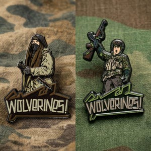 May include: Two enamel pins featuring military-themed illustrations. One pin depicts a figure in a military uniform holding a weapon, and the other shows a figure with a weapon. Both pins have the text "WOLVERINES!" in a stylized font.