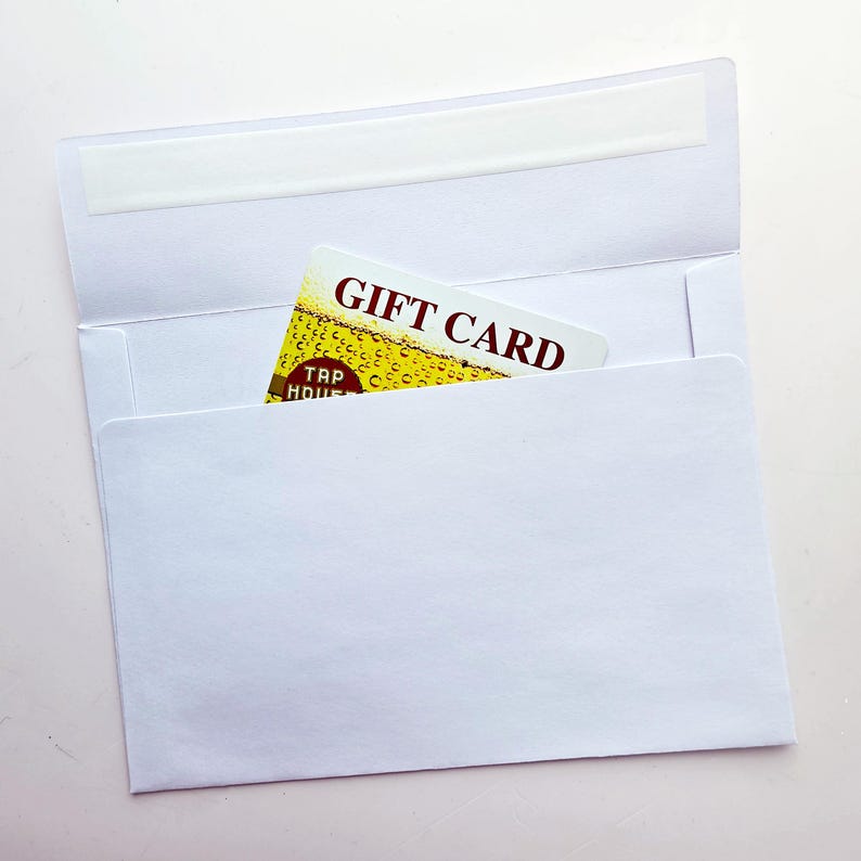 May include: A white paper envelope with an open flap containing a rectangular gift card. The card features a yellow beer-themed graphic with bubbles and the text GIFT CARD and TAP HOUSE printed in dark red letters on the front surface.