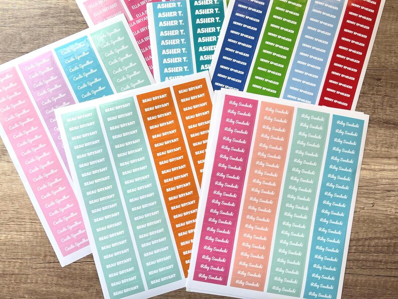 May include: Sheets of colorful name labels with names printed in white. The labels are in various colors, including pink, blue, green, orange, and red. The names are printed vertically.