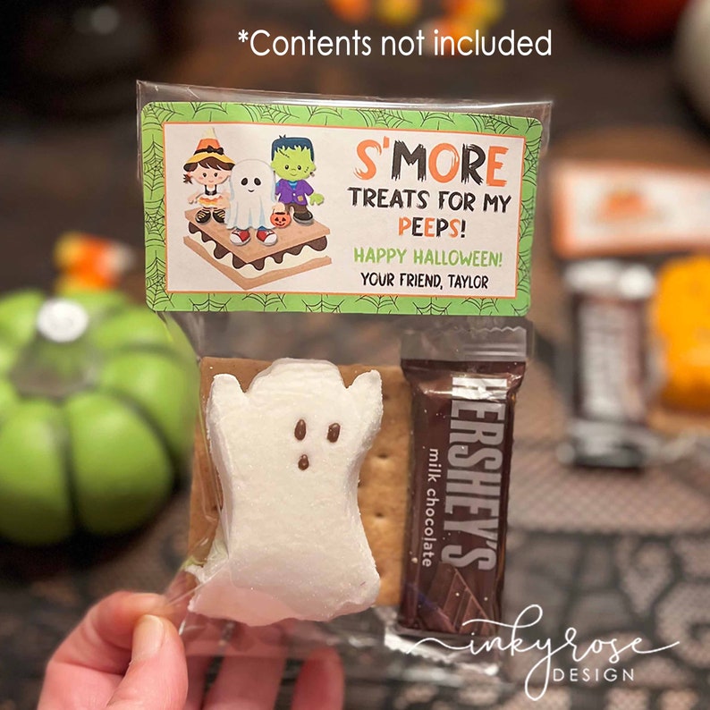May include: A clear plastic bag filled with a s'more treat for Halloween. The bag contains a graham cracker, a ghost-shaped marshmallow, and a Hershey's chocolate bar. The bag has a green and white label that says "S'more Treats for My Peeps! Happy Halloween! Your Friend, Taylor."