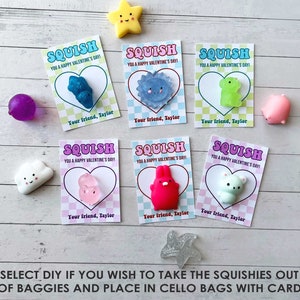 May include: Six Valentine's Day cards with the word "SQUISH" printed on them. Each card features a different colorful squishy toy, including a cloud, a bunny, a bear, a frog, a fish, and a heart. The cards are on a light wood background.