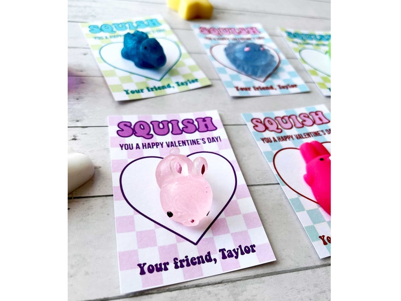 May include: Four Valentine's Day cards with the word "SQUISH" printed on them. Each card has a different colored heart-shaped squishy toy attached to it. The text on the card reads "You a Happy Valentine's Day!" and "Your friend, Taylor".