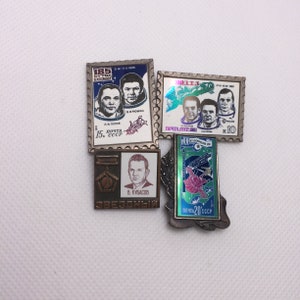 May include: Four vintage Soviet era postage stamps featuring astronauts and space exploration. The stamps are silver and blue with red and white accents. The stamps feature the text "185 суток в космосе", "103 T-3", "ПОЧТА СССР 1981", and "ПОЧТА 20 СССР 1977".