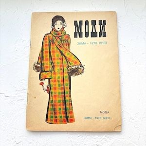 May include: Vintage fashion magazine cover featuring a woman in a plaid coat with fur trim. The coat is yellow, orange, and green. The magazine title is in bold black letters, with Cyrillic text below. The cover has a worn, aged appearance.