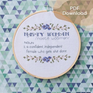 Peut inclure: Un cercle de broderie au point de croix avec l'inscription "NASTY WOMAN" et une définition, orné de motifs floraux. Le design comprend le texte "PDF Download". Le fond est un motif géométrique dans les tons de vert et de bleu.