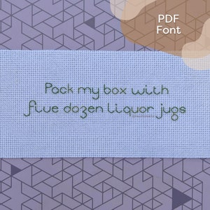 Pode incluir: Um tecido azul claro com o texto "Pack my box with five dozen liquor jugs" bordado em fio verde.