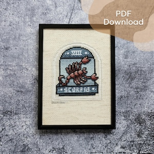 May include: Framed cross-stitch art featuring a scorpion, the zodiac sign for Scorpio. The scorpion is in shades of red and brown, set against a light blue background. The word "SCORPIO" is stitched below the scorpion.