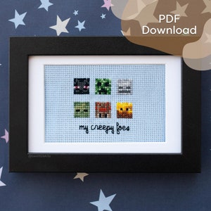 May include: A framed cross-stitch artwork with six pixelated monster designs in black, green, and orange on a light blue background. The words "my creepy foes" are stitched below. The frame is black. The image is a PDF download.