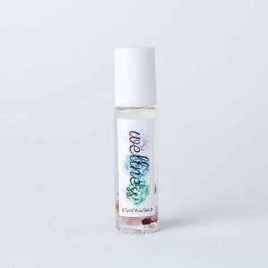May include: A clear glass roller bottle with a white cap and a label that says "wellness" in a decorative font. The label also features a watercolor design of flowers and crystals.