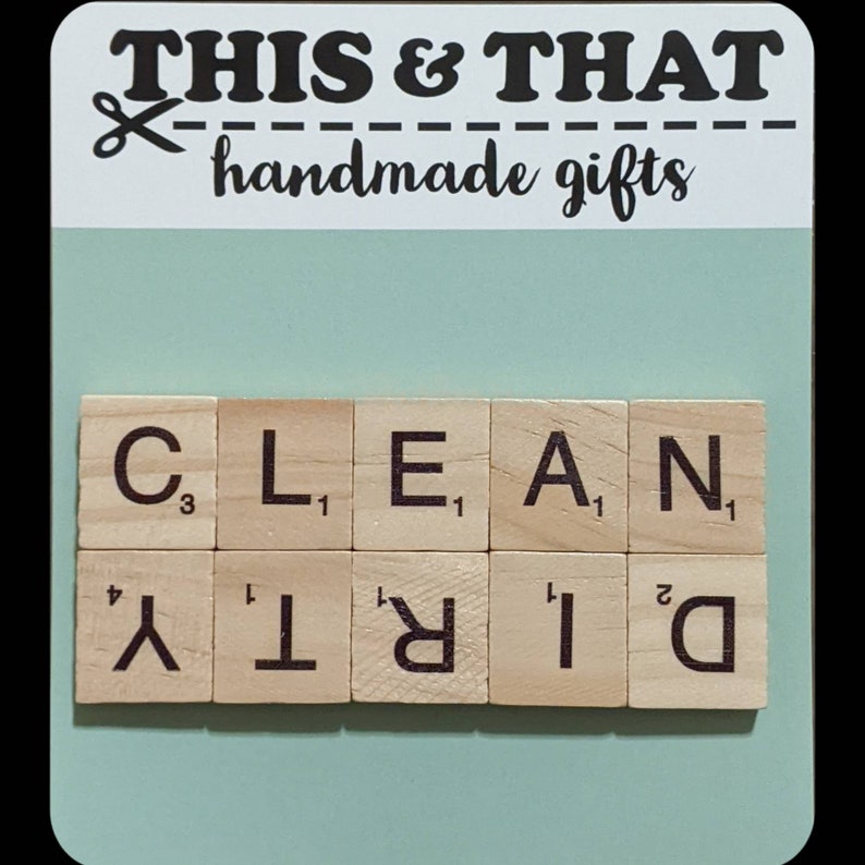 May include: A wooden sign with the text "THIS & THAT handmade gifts" and a pair of scissors. Below the sign are wooden letter tiles spelling out "CLEAN" and "DIRTY".