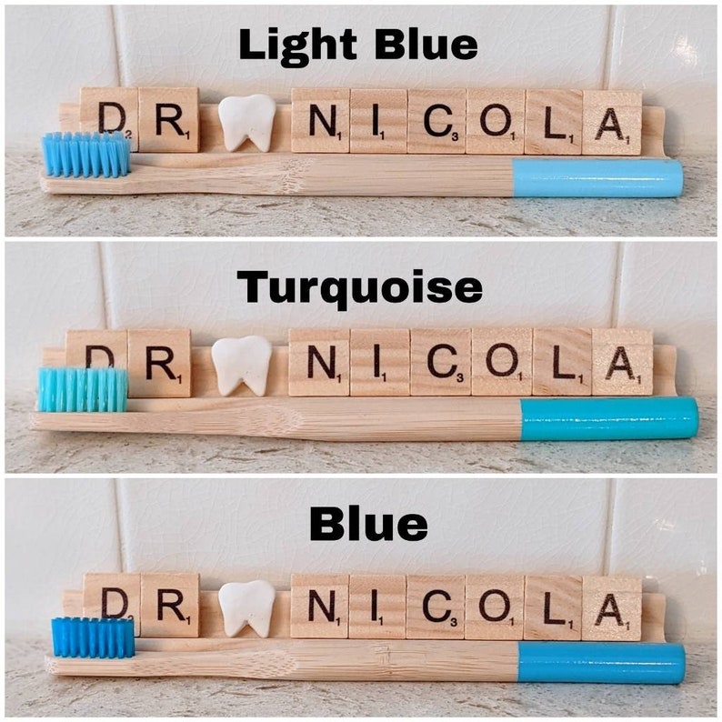 May include: Three wooden toothbrushes with different colored bristles: light blue, turquoise, and blue. Each toothbrush has a white tooth charm and the letters "DR NICO, L, A" spelled out with wooden letter tiles.