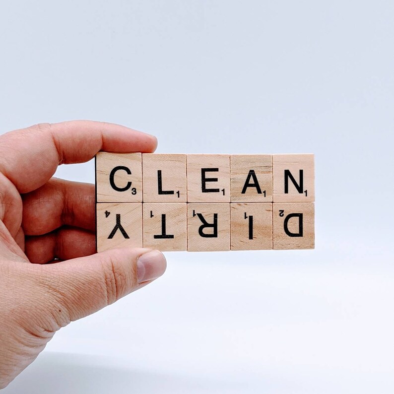 May include: Wooden letter tiles spelling out the words "CLEAN" and "DIRTY" in a hand.