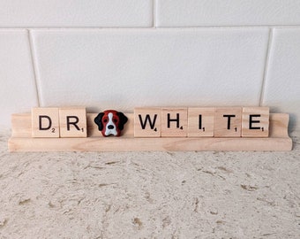May include: The word "WHITE" spelled out using wooden letter tiles. The letter "W" is a double letter score tile. A small, brown, black, and white dog figurine is placed between the letters "R" and "W".