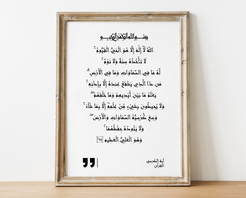 Peut inclure: Une impression encadr&eacute;e d'un texte islamique en &eacute;criture arabe. Le texte est en encre noire sur fond blanc. Le cadre est en bois brun clair avec une bordure dor&eacute;e. Le texte est tir&eacute; du Coran, plus pr&eacute;cis&eacute;ment du verset connu sous le nom d'&laquo;&nbsp;Ayat al-Kursi&nbsp;&raquo; ou &laquo;&nbsp;Le verset du Tr&ocirc;ne&nbsp;&raquo;.
